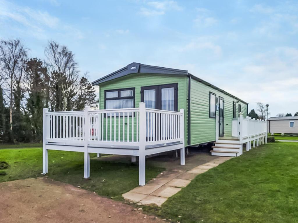 a green tiny house with a white porch at Snowdonia View in Pwllheli