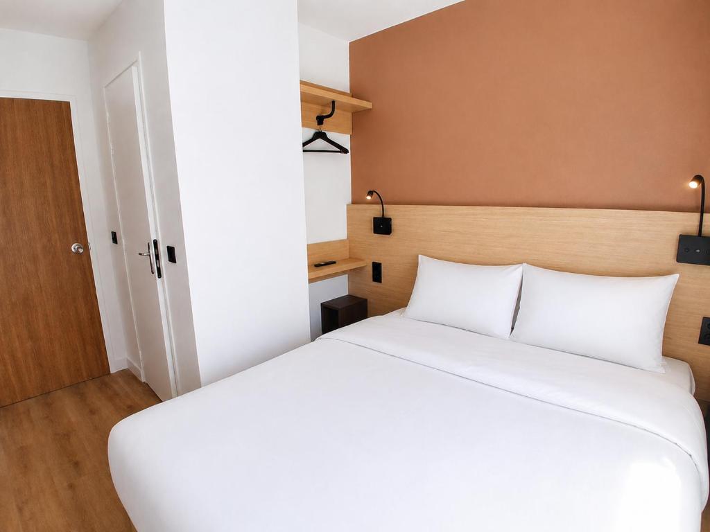 a bedroom with a white bed and a brown wall at Kyriad ECO - Tours Nord in Tours