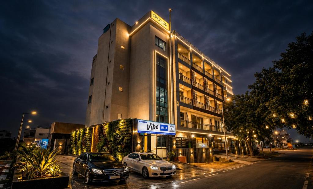 a building with two cars parked in front of it at Hotel Vibe BLU & Banquet Near Advant, Embassy Oxygen & Sector 142,143 Metro, Noida in Noida