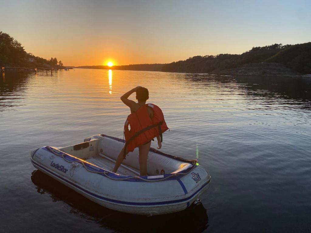 a man in a boat on the water at sunset at Hällestrand Semesterby R19 in Strömstad