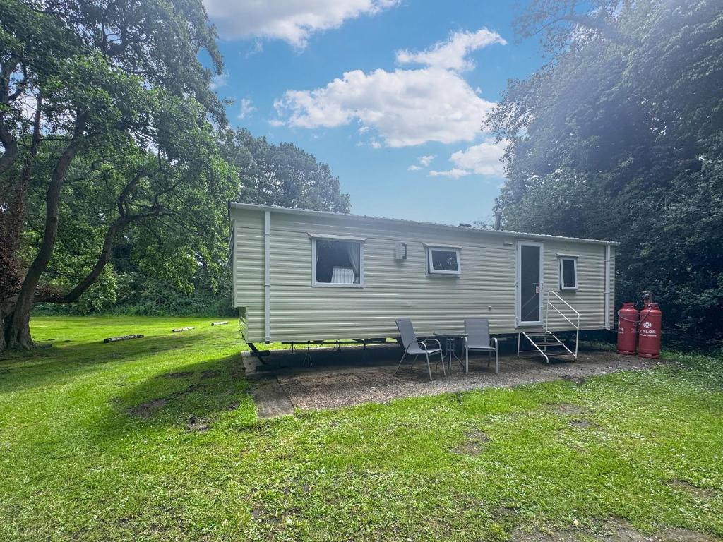 a small caravan in a field with two chairs at Mallard - Uk52121 in Hevingham