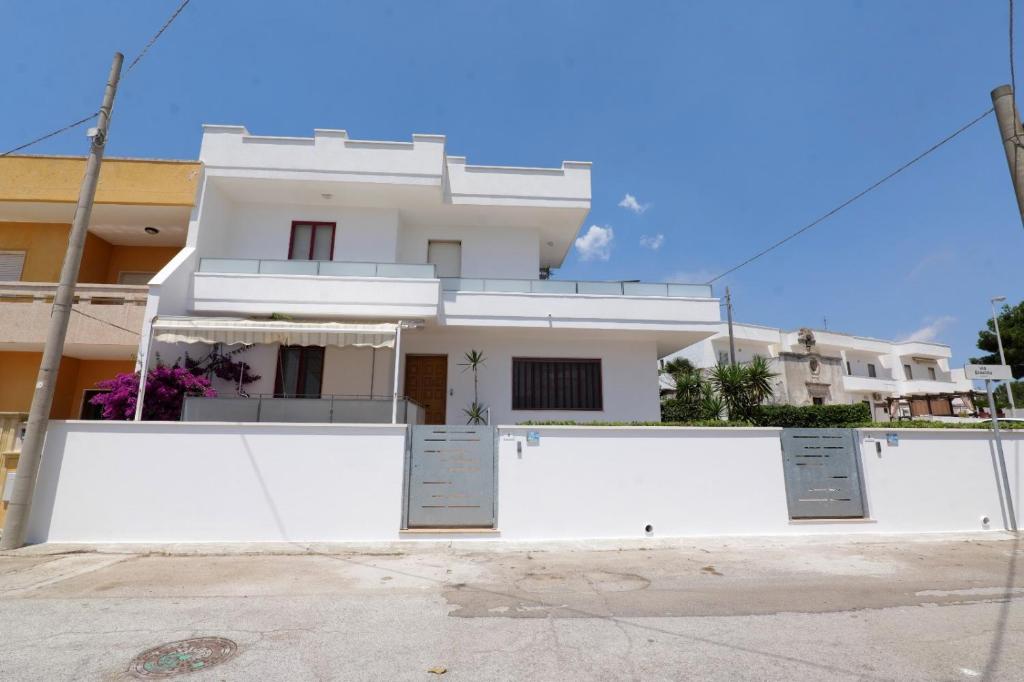 a white house with a fence in front of it at cmv Salento in Marina di Pescoluse