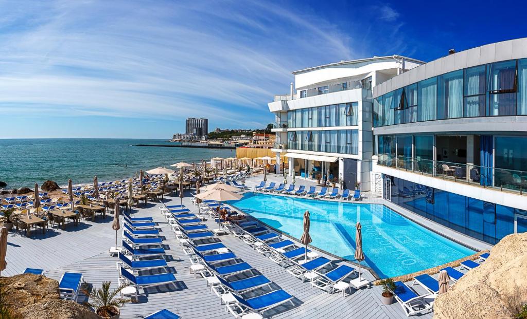 a hotel with a swimming pool and chairs and the ocean at Boutique Hotel Portofino in Odesa