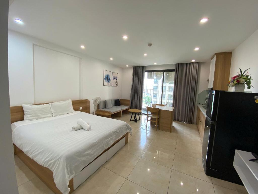 a bedroom with a bed and a kitchen and a table at Vinhomes D'Capitale - Amee Apartment in Hanoi