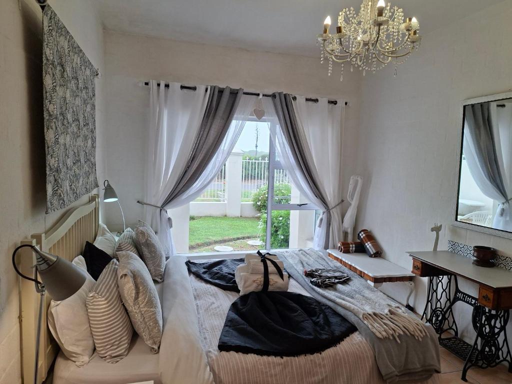 a bedroom with a bed and a chandelier and a window at DolfinHouse in Yzerfontein
