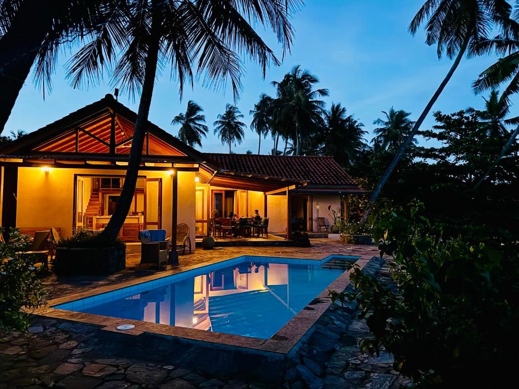 a villa with a swimming pool in front of a house at Blue Beach Villa - Nilwella in Matara