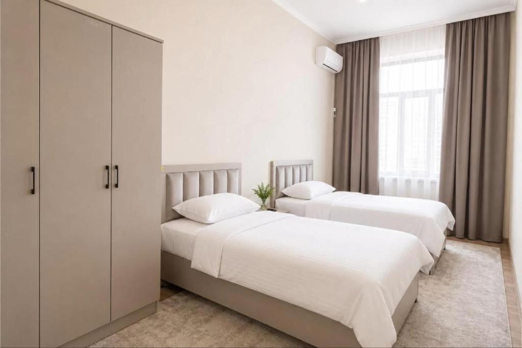 two beds in a bedroom with white walls and windows at Datka Hotel in Bishkek