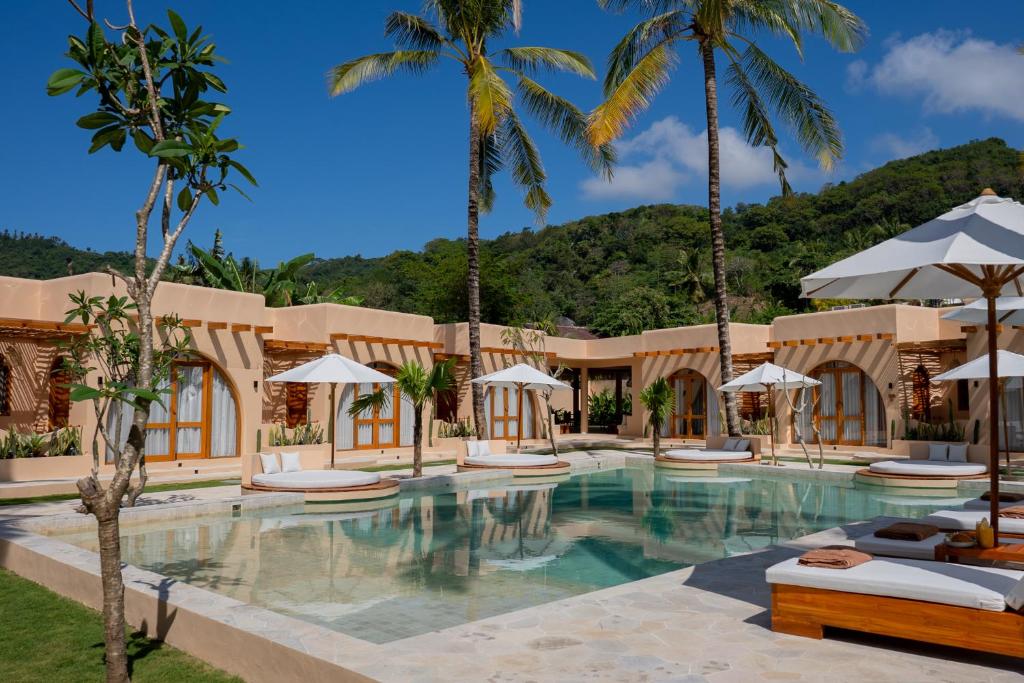 a resort with a swimming pool with palm trees at Miliyana Boutique Hotel - Adults Only in Kuta Lombok