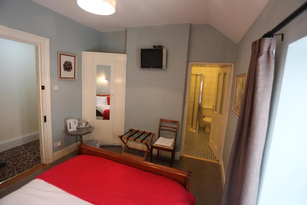 a bedroom with a bed and a chair and a television at Rolling Wave Guesthouse in Bundoran