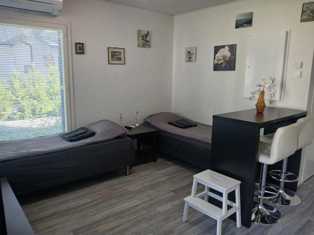 a room with two beds and a desk and a table at Cozy Studio Järvenpää in Järvenpää