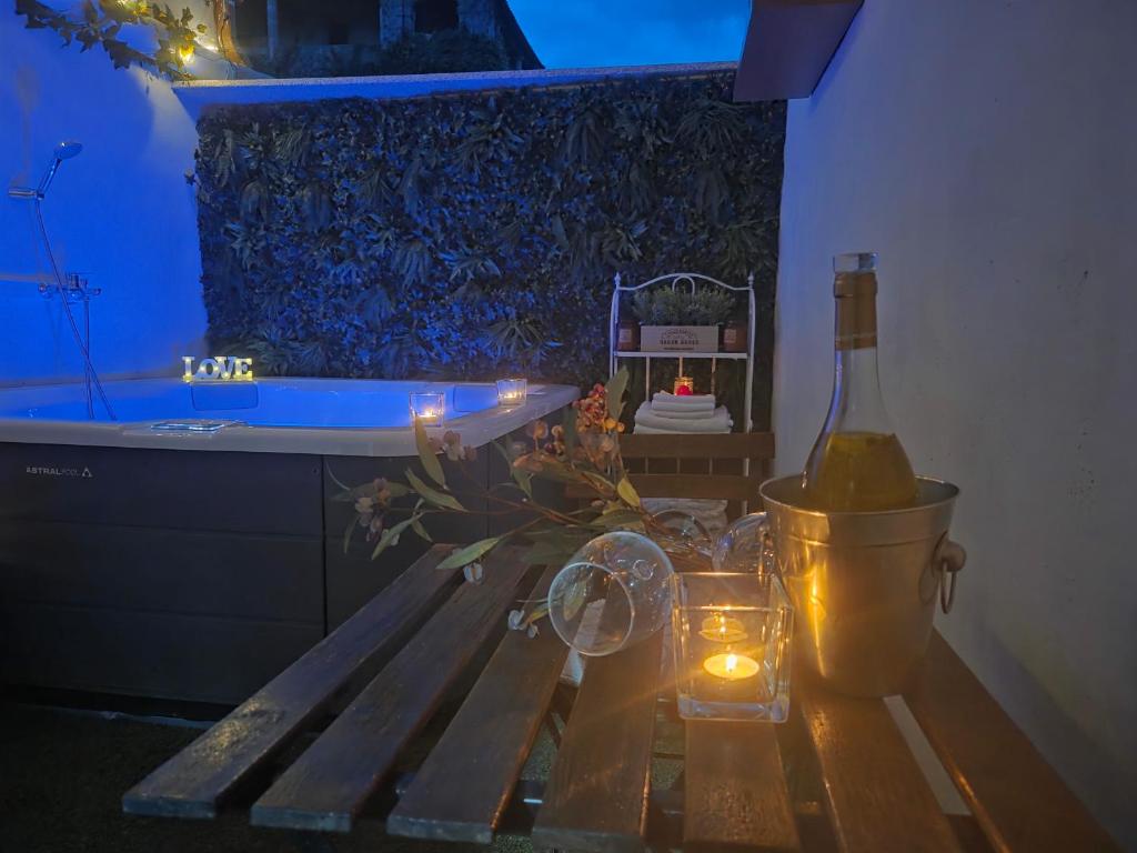 a bathroom with a bench with a bottle of wine and a candle at El Secreto de Boada Spa privado & Restaurante Adults Only in Villamiel