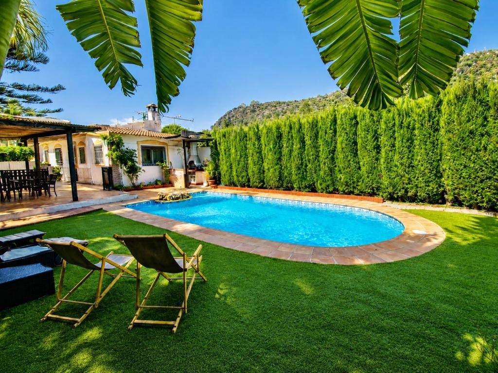 a yard with a swimming pool and two chairs at Velez Nazari Cortijo Azud in Vélez de Benaudalla