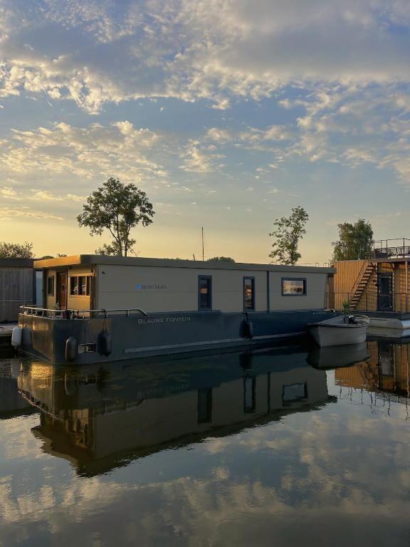 a boat is docked in the water with a building at The Creative Boat - Sneekermeer in Offingawier