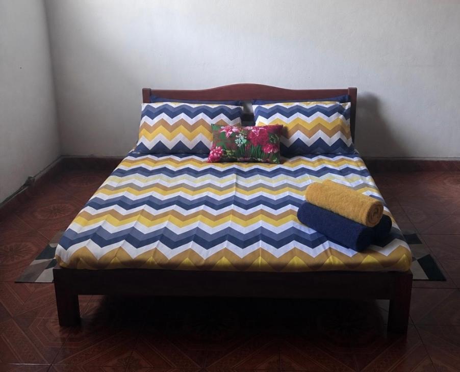 a bed with colorful pillows on it in a room at LE Triomphe in Antsiranana