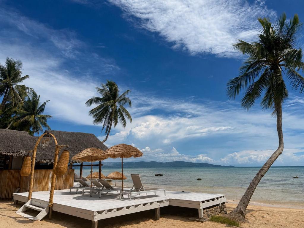 a beach with chairs and umbrellas and the ocean at Last Hammock Beach Resort in Baan Khai