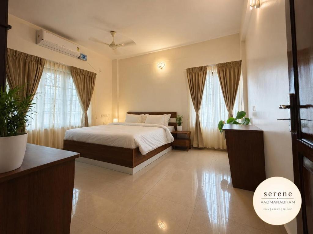 a bedroom with a bed and two windows at Serene Padmanabham Premium Luxury Apartments Near Sree Padmanabhaswamy Temple in Trivandrum