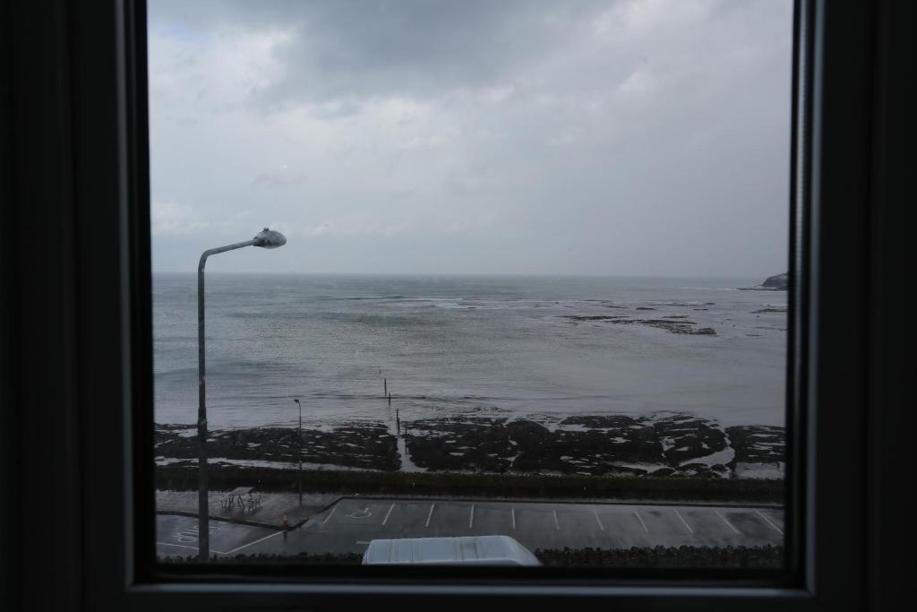 a window with a view of the ocean and a street light at Rolling Wave Guesthouse in Bundoran