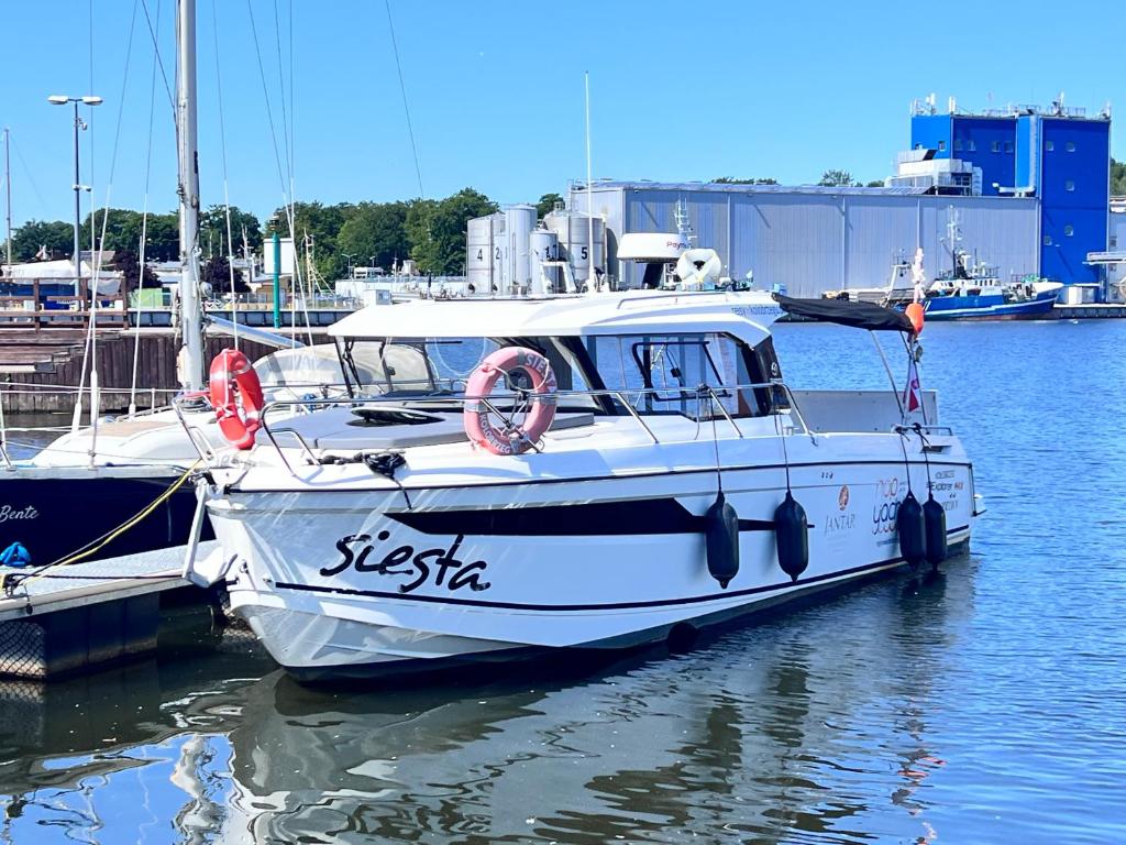a white boat docked at a dock in the water at Siesta Luxury Love Boat - NOCLEG NA ŁODZI W MARINIE SOLNEJ in Kołobrzeg