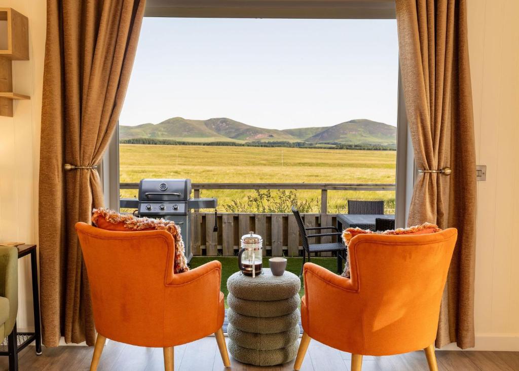 a living room with orange chairs and a large window at Scald Law in Penicuik