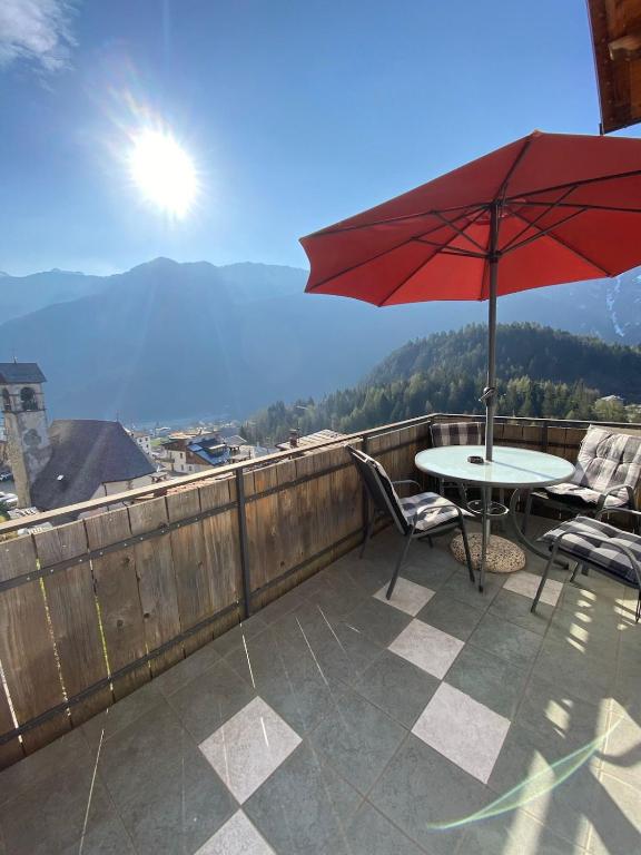 a patio with a table and chairs and an umbrella at La Casa del SEI SERIO in Pieve di Cadore