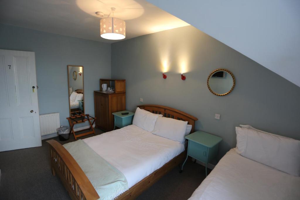 a bedroom with two beds and a mirror at Rolling Wave Guesthouse in Bundoran