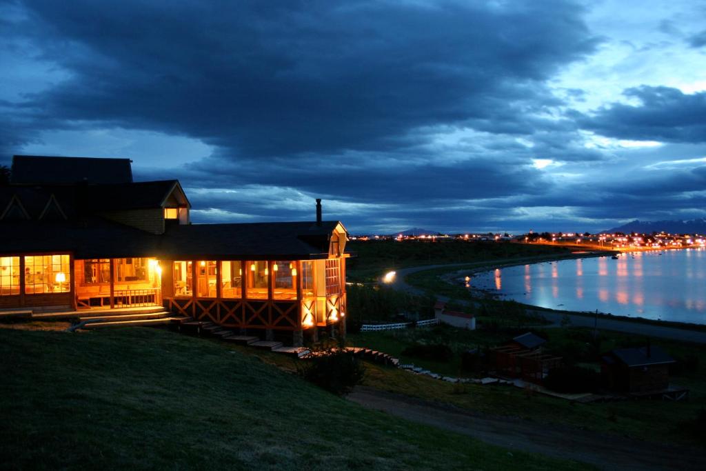 une maison sur la rive d'un lac la nuit dans l'établissement Weskar Lodge Hotel, à Puerto Natales