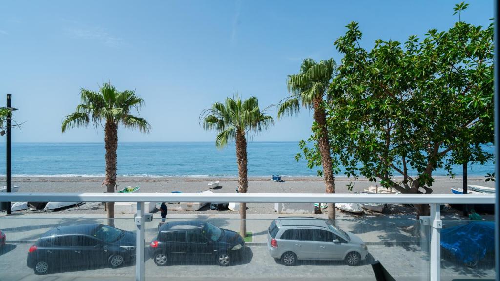 a view of a beach with palm trees and cars at Casa Las Conchas in La Rábita