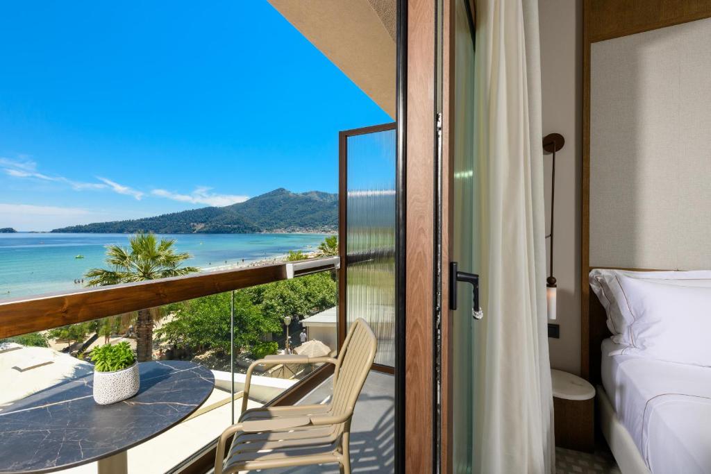 a room with a balcony with a bed and a view of the ocean at Enavlion Elegance Seaside Luxury in Chrysi Ammoudia