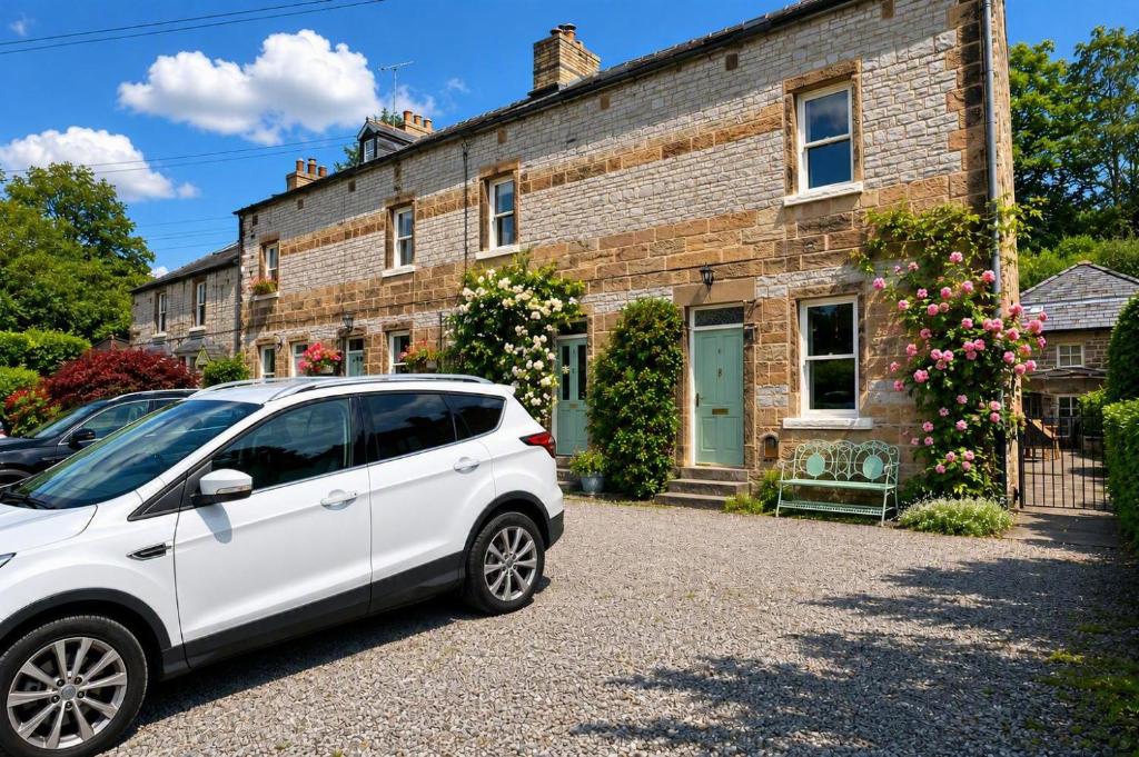 a white car parked in front of a brick house at Brookfield Cottages in Bakewell