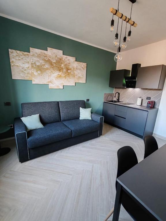 a living room with a blue couch and a kitchen at Manu & Manu Rooms in Garlenda