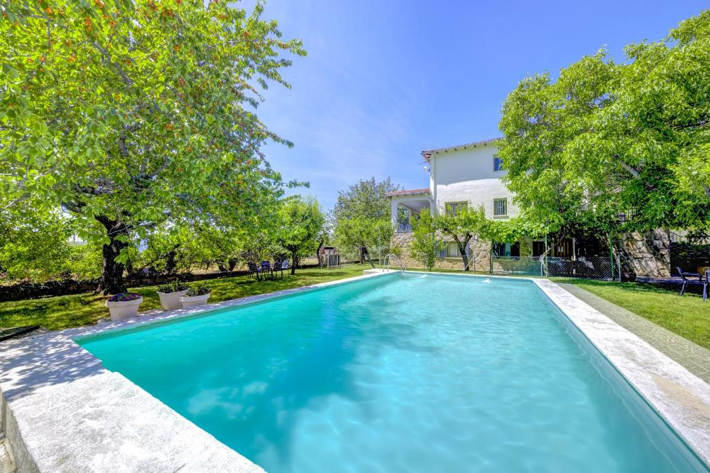 a swimming pool in front of a house at Villa-Piedralaves-aMatalasviñas-piscina-4 viviendas in Piedralaves