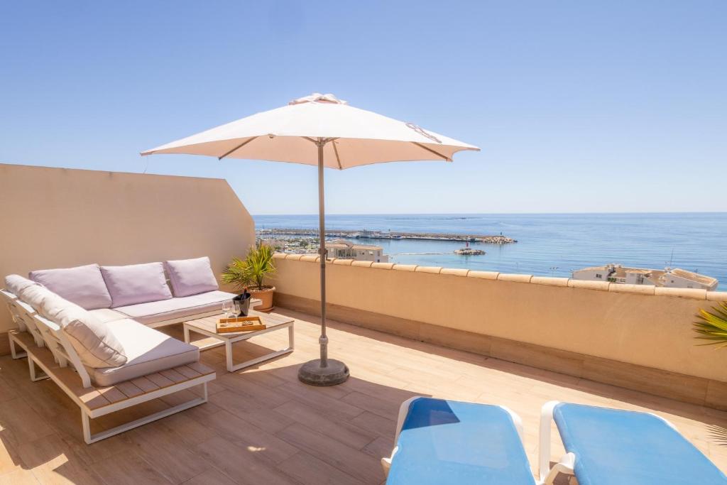 a patio with an umbrella and chairs and the ocean at Suites At Sea II in Villajoyosa