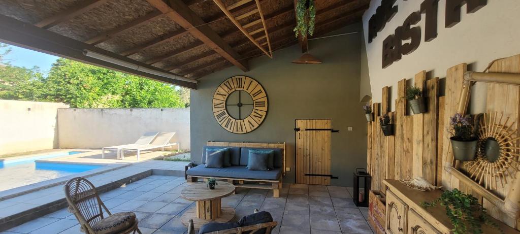 a patio with a pool and a clock on the wall at Gîte la Cabridello in Barbentane
