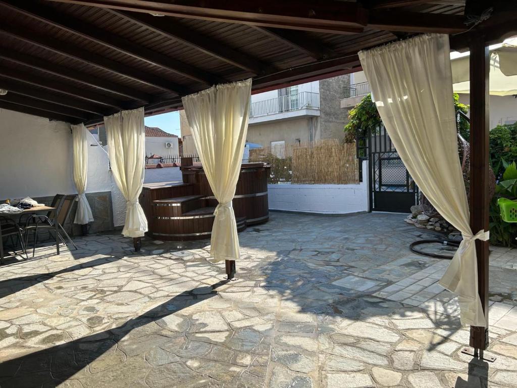 a patio with curtains and a table and a couch at Denis House in Keramoti