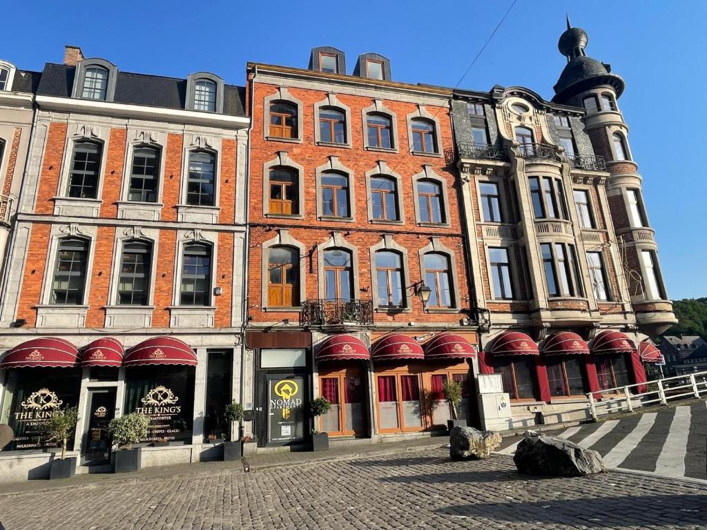 a large red brick building on a street at NOMAD APARTMENTS - Côté Meuse in Dinant