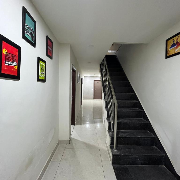 a hallway with stairs and paintings on the walls at Wellawing Regency Samrala Chownk in Ludhiana