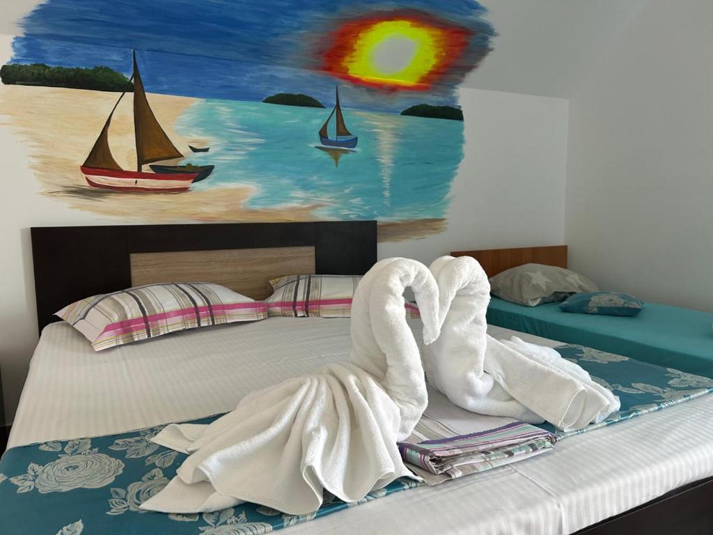 a bed with swan towels on it with a painting at EL Capitano - Mamaia Nord in Mamaia Sat/Năvodari