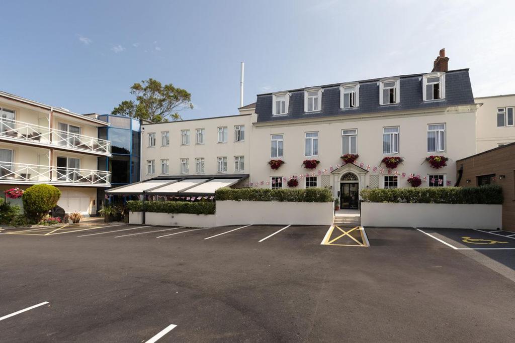 a parking lot in front of a white building at Les Rocquettes Hotel in St. Peter Port