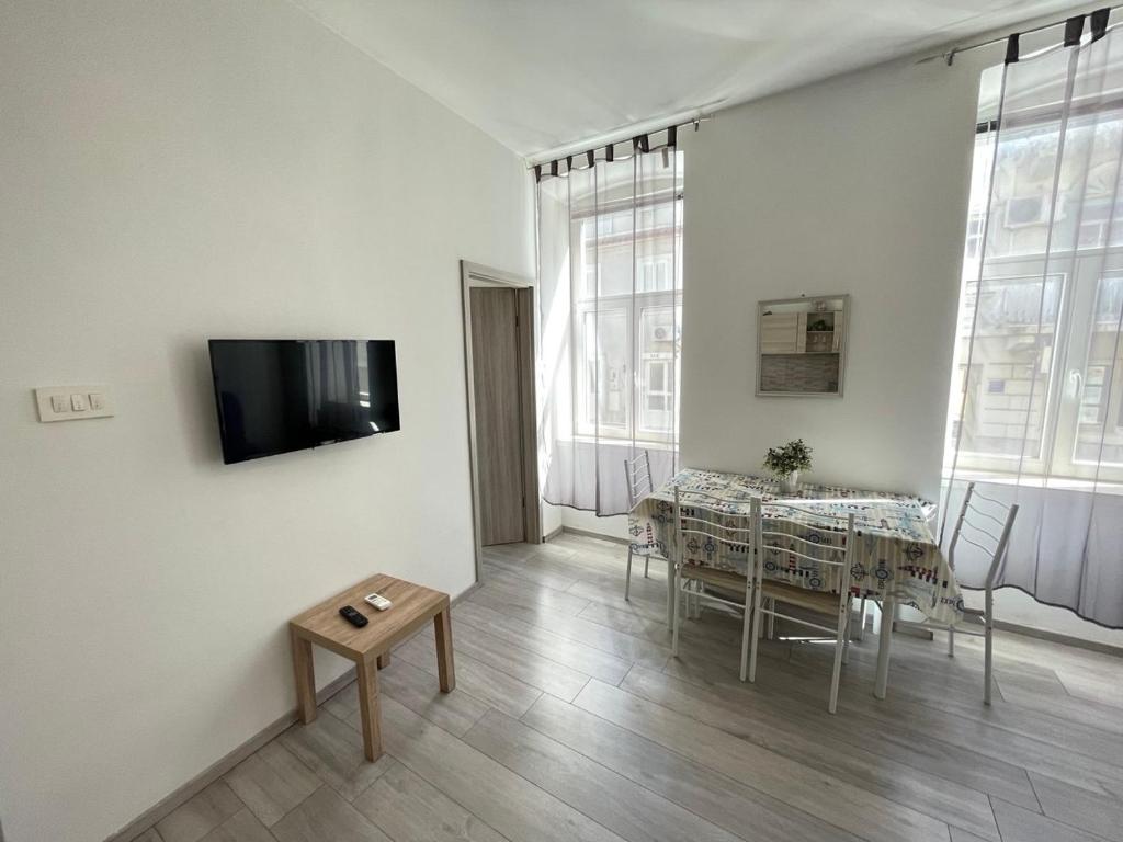 a living room with a table and a tv on a wall at Villa History in Crikvenica