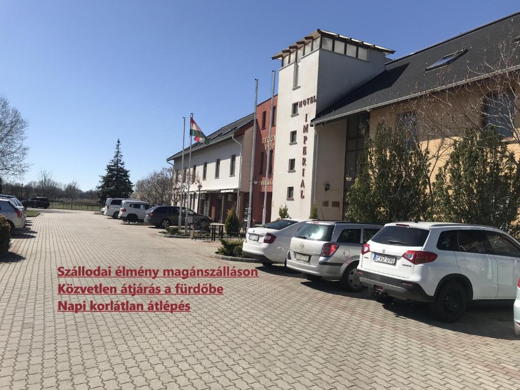 a parking lot with cars parked in front of a building at Thermal Apartman 01 in Kiskőrös