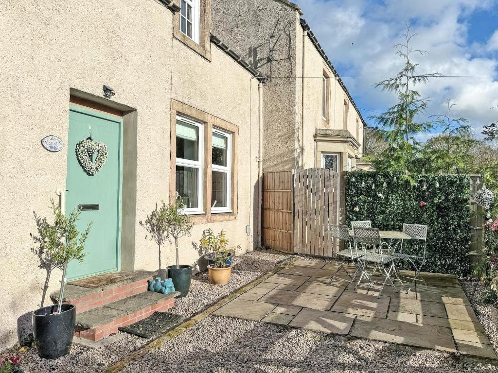 a house with a blue door and a patio at Leaderfoot Cottage in Selkirk
