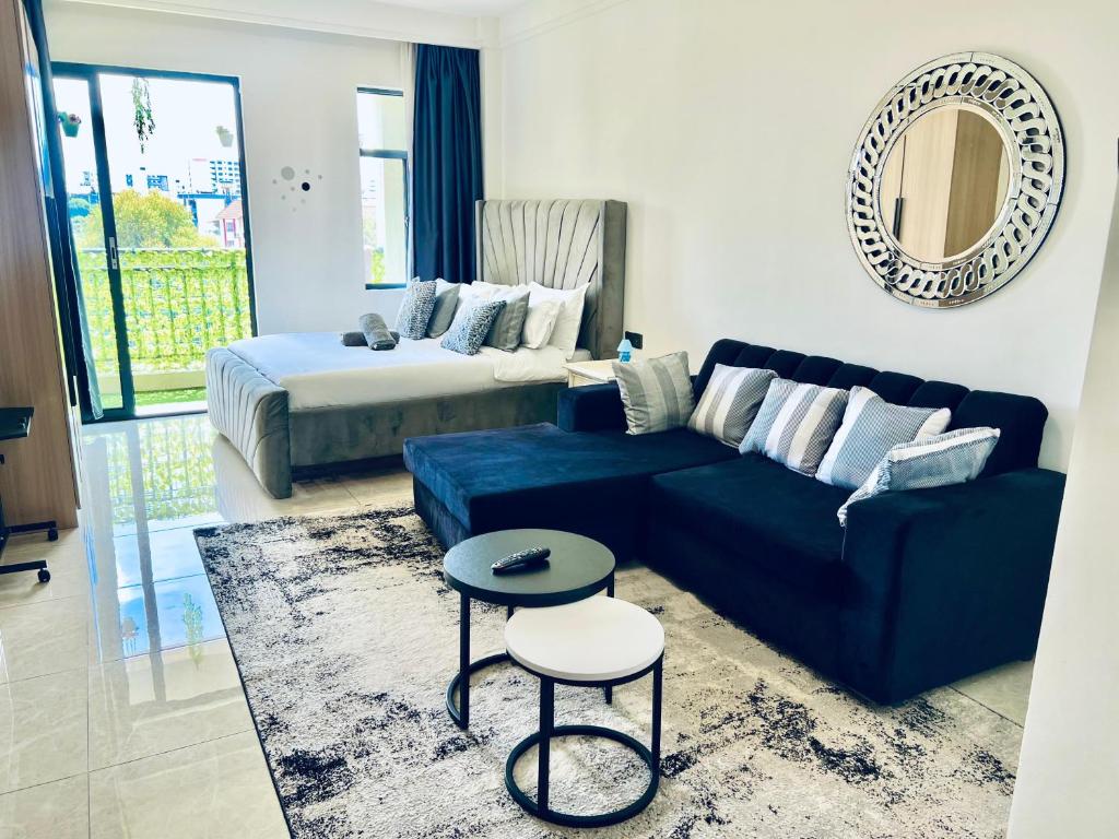 a living room with a blue couch and a bed at Nyvin Haven at The Loftel in Ruaka