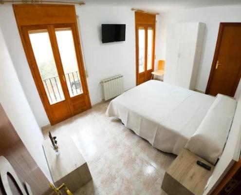 a bedroom with a white bed and a television at Hostal de Berge in Berge