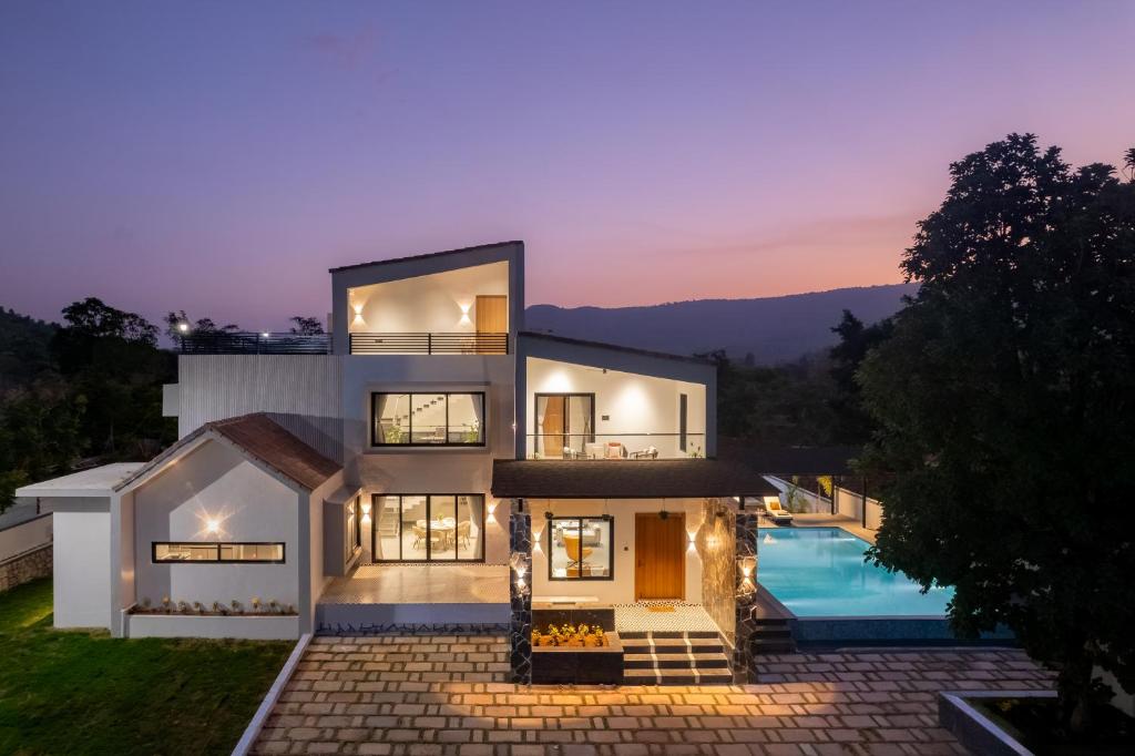 a house with a swimming pool at night at Saffronstays Crimson Crest in Khopoli