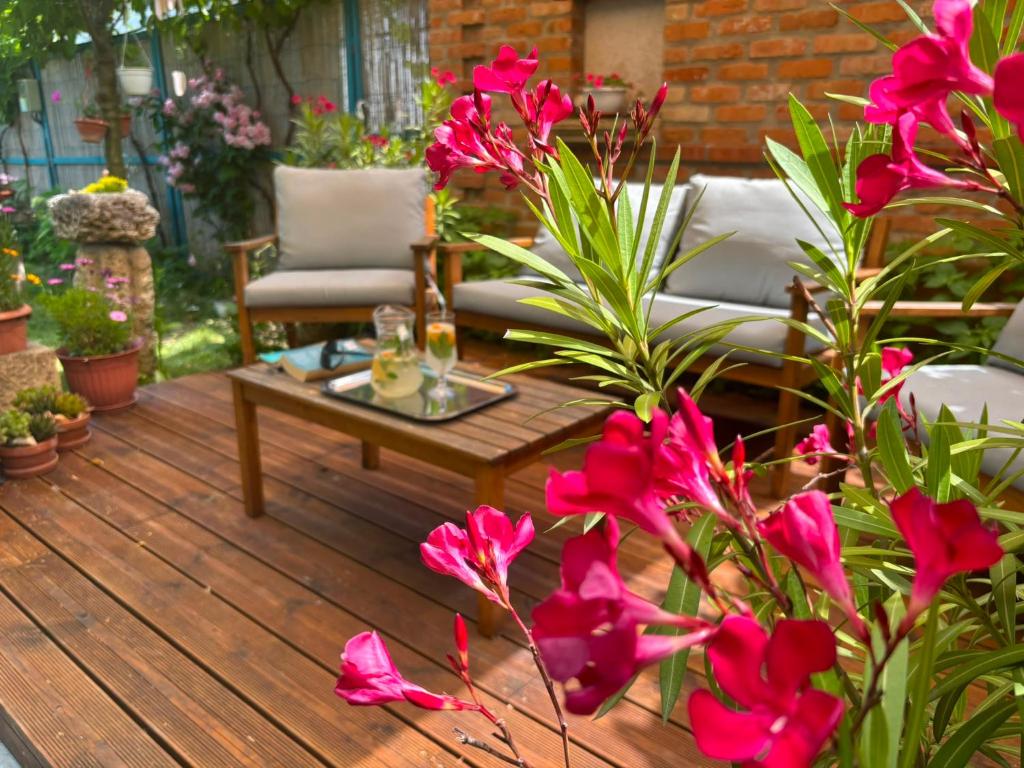 a wooden deck with a table and pink flowers at Casa David&Alexia 2 Mai in 2 Mai