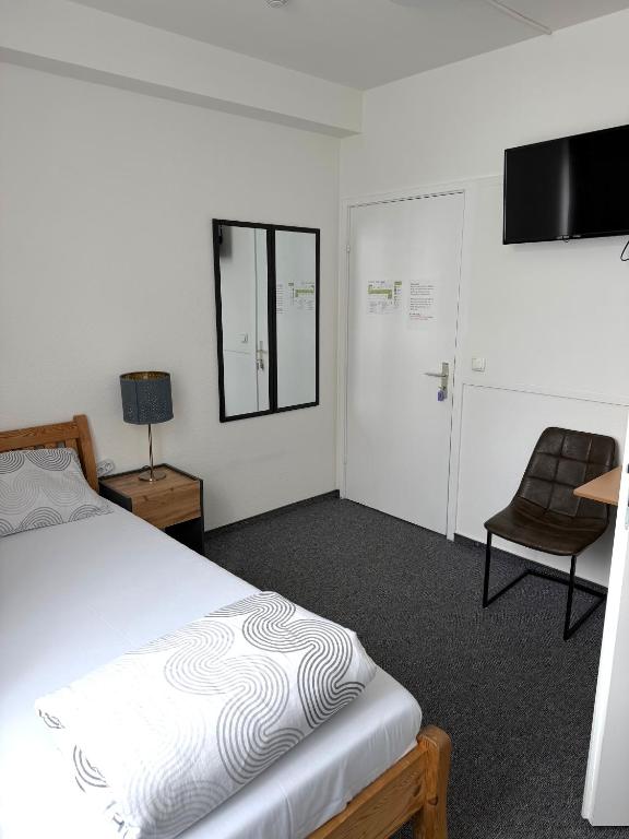 a bedroom with a bed and a chair and a television at Hotel Wandsbek Hamburg in Hamburg