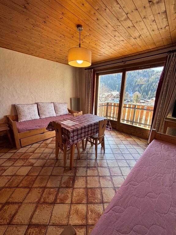 a room with a table and a couch and a window at Studio Crêt du Midi, Chez Francine in Notre-Dame-de-Bellecombe
