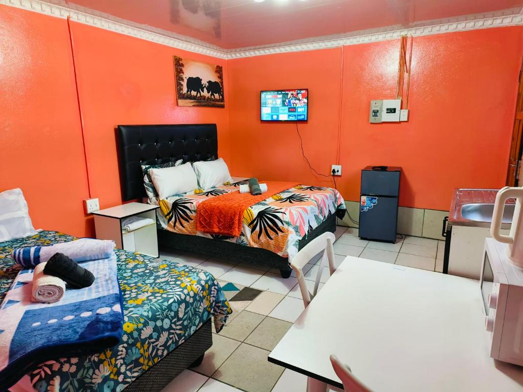 a room with two beds and orange walls at 48 ON Lindi in Welkom