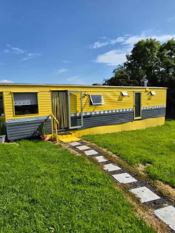 a yellow house sitting on top of a lush green field at Airport Cottage in Aldergrove