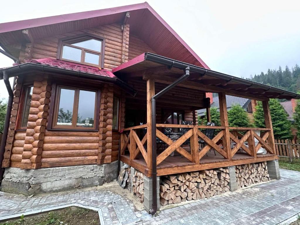 a log cabin with a porch and a fence at Андріана in Mykulychyn